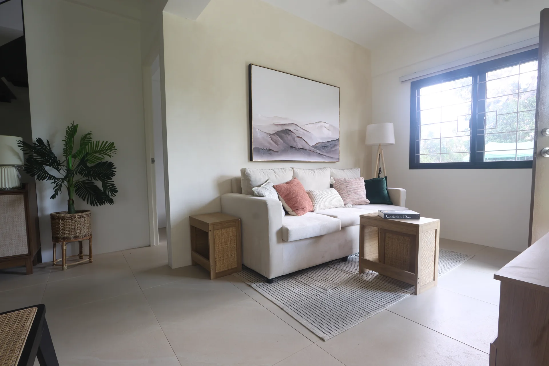 Larissa living room with a neutral sofa, timber tables, and a large landscape artwork